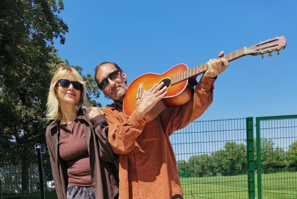 Pisateljica Nina Kosmač in glasbenik Klemen Tičar med igranjem kitare na prostem